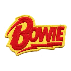 May include: A yellow and red embroidered patch with the word "BOWIE" in a stylised font.