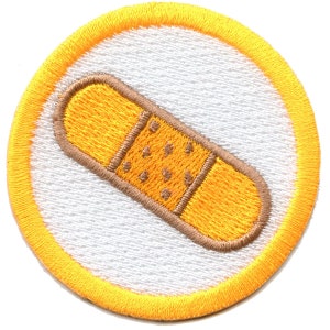 May include: A yellow and brown embroidered patch with a white background. The patch features a cartoon bandage with a brown border and yellow center.