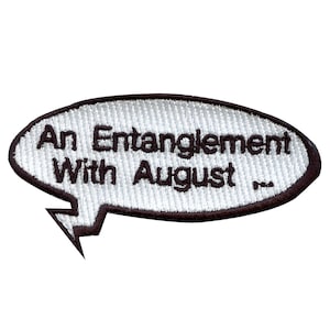 May include: White embroidered patch with a black outline in the shape of a speech bubble. The text inside the speech bubble reads "An Entanglement With August".
