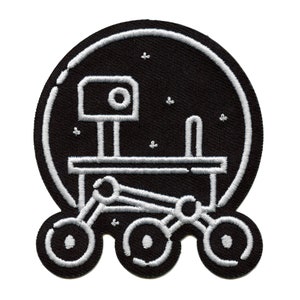 May include: A black and white embroidered patch depicting a rover with six wheels, a camera, and a robotic arm. The rover is surrounded by a circle and stars.