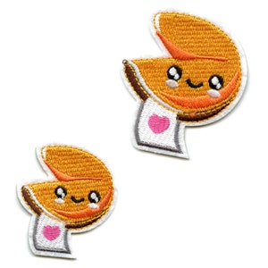 May include: Two embroidered iron-on patches of fortune cookies with happy faces and a pink heart on a white background.
