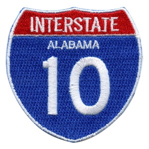 May include: Blue and red interstate highway sign with white text that reads "INTERSTATE ALABAMA 10".