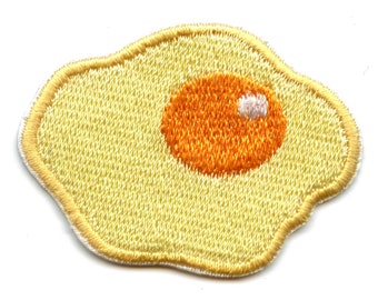 May include: A yellow embroidered patch shaped like a fried egg with an orange yolk and a white spot.