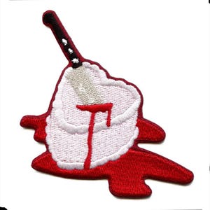 Op de afbeelding: Geborduurde patch met een kerstmanontwerp met een mes dat in zijn hoofd steekt. De patch heeft een witte baard en een rode hoed en pak, met een zilveren mes en rood bloed dat naar beneden druipt. De patch staat op een witte achtergrond.