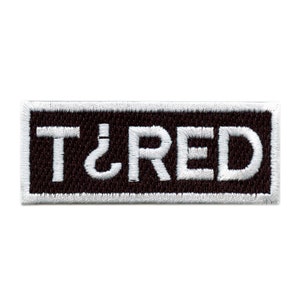 May include: White embroidered patch with a black background and the text "TIRED" in white.