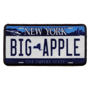 May include: A blue and white embroidered patch with the text "NEW YORK" and "BIG APPLE" with an outline of the state of New York in between the words. The text "THE EMPIRE STATE" is at the bottom of the patch.