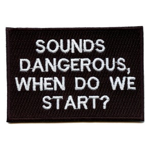 May include: Black embroidered patch with white text that reads "Sounds dangerous, when do we start?"