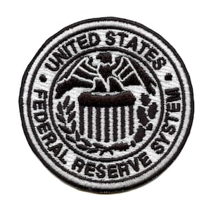 May include: A white and black embroidered patch with the words "United States Federal Reserve System" in a circle around a stylized eagle and a building with columns.