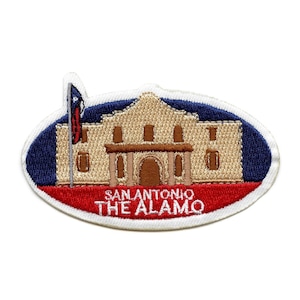 May include: Embroidered patch featuring a beige building with a red roof and a blue sky background. The building has a flagpole with a Texas flag on it. The text "SAN ANTONIO THE ALAMO" is written in white on a red banner below the building.