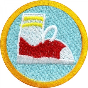 May include: A round, blue and yellow embroidered patch with a red and white shoe design. The shoe has a yellow stripe at the top.