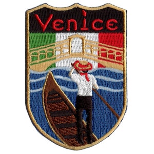 May include: Embroidered patch with a blue background, a gondola, a gondolier, and the Italian flag. The text "Venice" is in red letters on a black background.