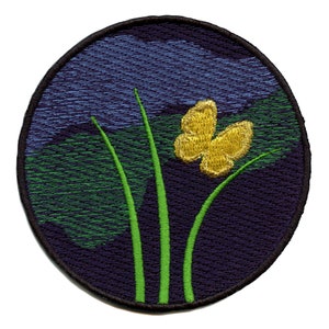 May include: A round embroidered patch with a yellow butterfly and green grass on a dark blue background.