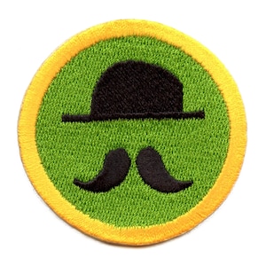 May include: A green and yellow embroidered patch with a black bowler hat and mustache.