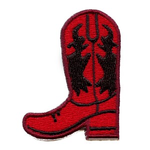 Könnte beinhalten: Ein roter, gestickter Aufnäher in Form eines Cowboy-Stiefels. Der Stiefel hat ein schwarzes Zierdesign auf dem Schaft und schwarze Verzierungen. Der Aufnäher ist zum Aufbügeln oder Aufnähen auf Stoff gedacht.