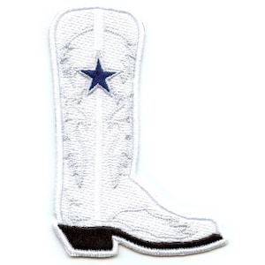 May include: White embroidered patch in the shape of a cowboy boot. A blue star is centered on the boot. The heel is dark brown. The patch is designed to be sewn or ironed onto fabric.