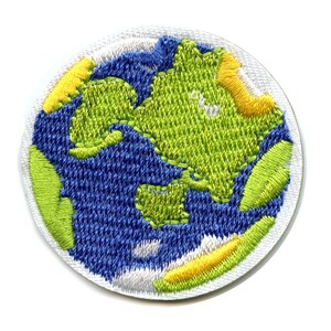 May include: Circular embroidered patch depicting the Earth. The design features blue oceans, green continents, and yellow accents, all set against a white border. The patch is made of stitched fabric.