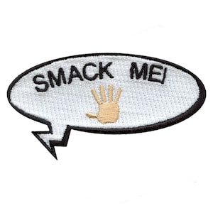 May include: White oval-shaped patch with black stitching and a black outline. The patch has the text "SMACK ME!" in black lettering and a beige handprint in the center.