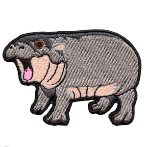 May include: Embroidered patch featuring a cartoon hippopotamus with an open mouth. The hippo is primarily gray with tan and pink accents, and a black border. The patch is designed to be ironed on or sewn onto fabric.