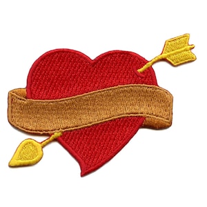 Puede incluir: Corazón rojo con una cinta dorada y una flecha que lo atraviesa. La cinta tiene espacio para texto.