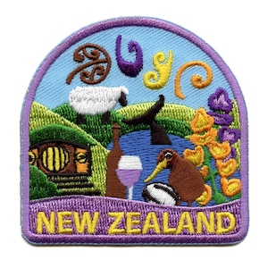 Może przedstawiać: Kolorowa haftowana naszywka z napisem "NEW ZEALAND" w żółtych literach na fioletowym tle. Naszywka przedstawia kiwi, owcę, kieliszek wina, butelkę wina, piłkę do rugby, tradycyjny wzór maoryski i mały domek.