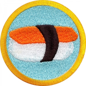 Könnte beinhalten: Ein runder, gelb umrandeter Aufnäher mit einem gestickten Bild einer Sushi-Rolle. Das Sushi besteht aus weißem Reis, orangem Fisch und einer schwarzen Seetang-Ummantelung.