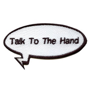 May include: White embroidered iron-on patch with a speech bubble shape and the text "Talk To The Hand" in black.