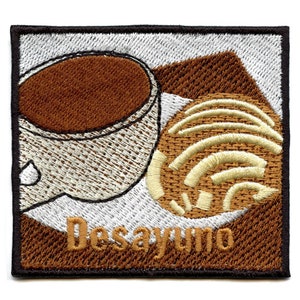 May include: Embroidered patch with a brown coffee cup and a sweet bread, with the word "Desayuno" in brown text.