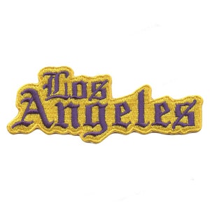 Könnte beinhalten: Ein gelber gestickter Aufnäher mit den Worten "Los Angeles" in lila Schrift.