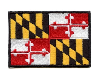 May include: An embroidered patch featuring the Maryland state flag. The flag is a black and gold chequered pattern with a red and white quartered design in the centre.