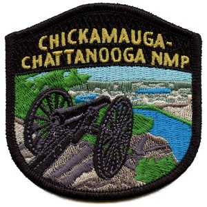 Pode incluir: Etiqueta bordada com fundo preto e texto dourado que diz "Chickamauga-Chattanooga NMP". A etiqueta apresenta um canhão preto em uma colina com vista para um rio azul e árvores verdes.