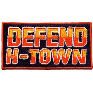 May include: An embroidered patch with the text "DEFEND H-TOWN" in orange and yellow letters on a dark purple background.