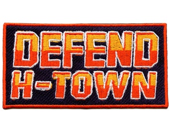May include: An embroidered patch with the text "DEFEND H-TOWN" in orange and yellow letters on a dark purple background.