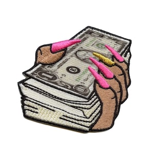 Peut inclure: Une pile de billets de banque tenue par des doigts avec du vernis à ongles rose et or.