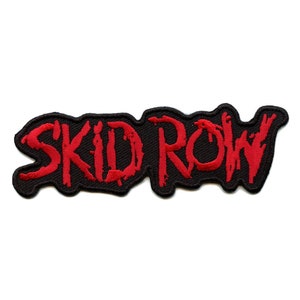 May include: Embroidered patch with the text "SKID ROW" in red, stylized lettering. The text is on a black background with a jagged border. The patch is likely for clothing or accessories.