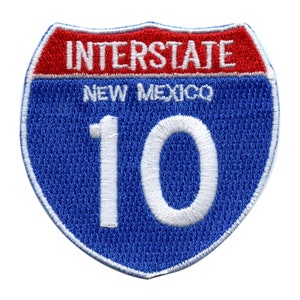 Op de afbeelding: Blauw en rood interstate snelweg bord met witte tekst "INTERSTATE NEW MEXICO 10".