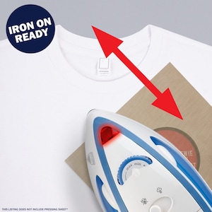 May include: A white t-shirt with a red arrow pointing to the top of the shirt. A white iron with a blue handle is on a brown surface with a red circle. The iron has a red light on the front and a dial with "max" and "min" settings. The text "IRON ON READY" is in a blue circle at the top of the image.