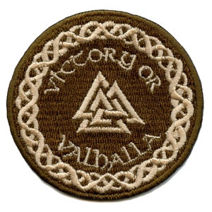 Könnte beinhalten: Ein brauner gestickter Aufnäher mit einem weißen keltischen Knotenrand. Die Mitte zeigt ein weißes Valknut-Symbol mit dem Text "ACCORD OF VALHALLA" darum herum.