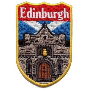 Op de afbeelding: Geborduurde patch met het woord "Edinburgh" in het wit op een rode achtergrond. Daaronder een blauw-wit ontwerp en een gedetailleerde illustratie van een stenen gebouw. De patch heeft een gele rand.