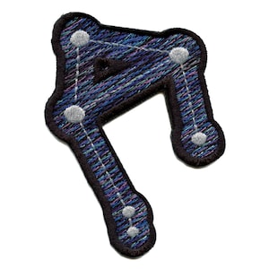 May include: A black embroidered patch with a constellation design. The constellation is outlined in white thread and has five white stars. The patch has a blue, purple, and pink background.