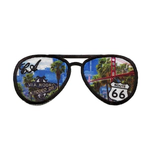 May include: A black and white embroidered patch of a pair of aviator sunglasses with a view of the Golden Gate Bridge and a Route 66 sign in the right lens and a view of Rodeo Drive in Los Angeles in the left lens.