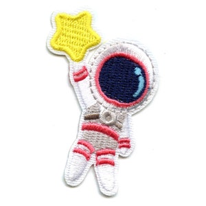 May include: An embroidered iron-on patch of a cartoon astronaut in a white spacesuit with pink accents, reaching up to hold a yellow star.