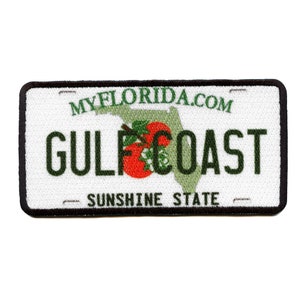May include: A white and green embroidered patch with a black border. The patch features a stylized outline of the state of Florida with a red tomato inside. The text "MYFLORIDA.COM" is at the top of the patch, and the text "GULF COAST" is in the center. The text "SUNSHINE STATE" is at the bottom of the patch.