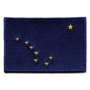 May include: A blue fabric patch with a yellow star and seven smaller yellow stars arranged in a diagonal line, representing the constellation Ursa Major, the Big Dipper.