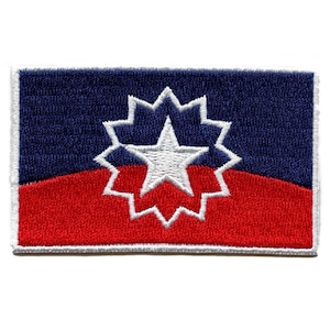 Puede incluir: Un parche bordado azul y rojo con una estrella blanca en el centro rodeada de un círculo blanco con 16 puntos.