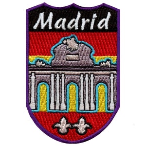 Peut inclure: Patch brodé de couleur pourpre et rouge avec le mot "Madrid" en lettres blanches. Le patch présente une image stylisée d'un bâtiment avec des arches et des colonnes.