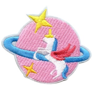 May include: A pink and white embroidered patch with a white unicorn with a blue and red mane and tail, a yellow star, and a blue ring around the unicorn. The patch is on a white background.