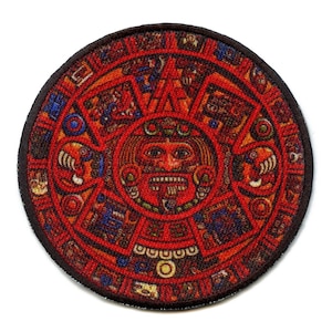 May include: Circular patch featuring a detailed Aztec calendar design. The patch is predominantly red with accents of orange, blue, and brown. The central figure is a face with an open mouth. The patch has a dark brown border.