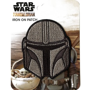 May include: Iron-on patch featuring a black and gray Mandalorian helmet from the Star Wars: The Mandalorian TV series. The patch is on a white background with a picture of the Mandalorian and Grogu.