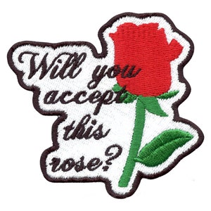 Może przedstawiać: Biała haftowana naszywka z czerwoną różą i tekstem "Will you accept this rose?"
