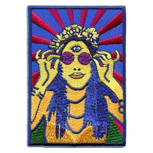 Może przedstawiać: Naszywka haftowana przedstawiająca kobietę z trzecim okiem, noszącą psychodeliczne okulary przeciwsłoneczne i wianek z kwiatów. Tło to wzór promieni słońca w kolorze niebieskim i czerwonym.
